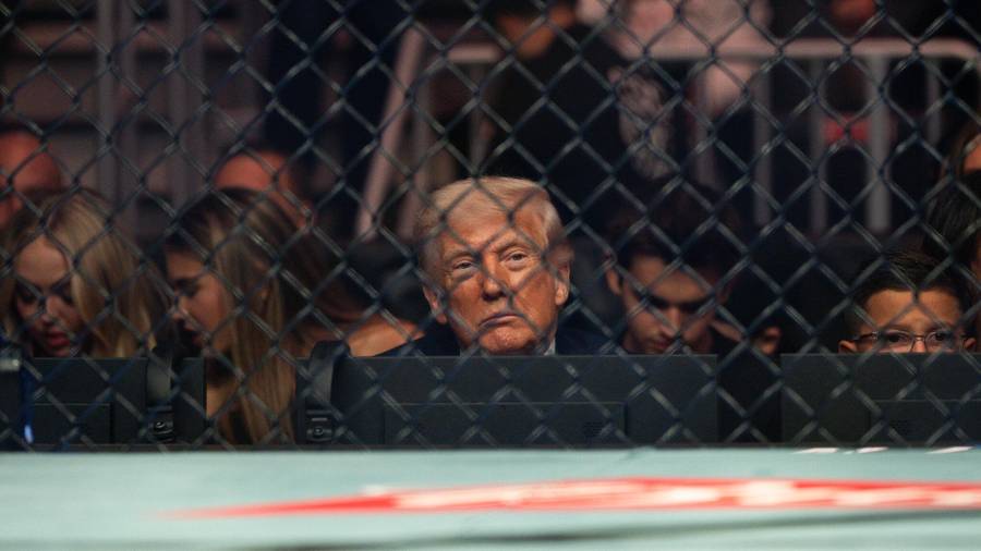 Donald Trump, visto a través de la valla metálica de un evento de la UFC, un reflejo de su aislamiento político y la presión creciente que enfrenta.