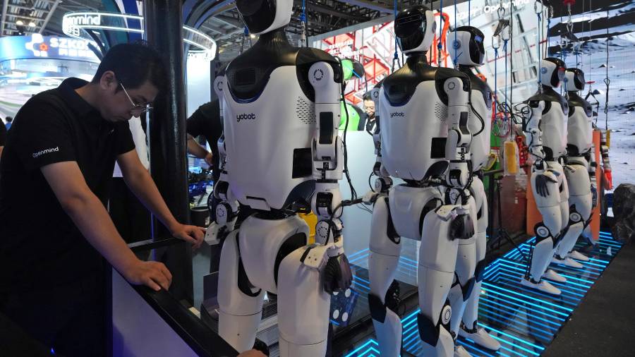 Un trabajador junto a una fila de robots humanoides en la conferencia World AI Conference en Shanghái, el viernes 17 de julio de 17, 2026.