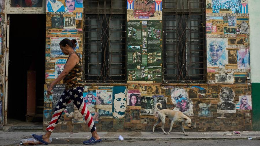 Una mujer pasa junto a un edificio en el que se exhiben fotografías del expresidente cubano Raúl Castro y del expresidente venezolano Nicolás Maduro, en La Habana, Cuba.