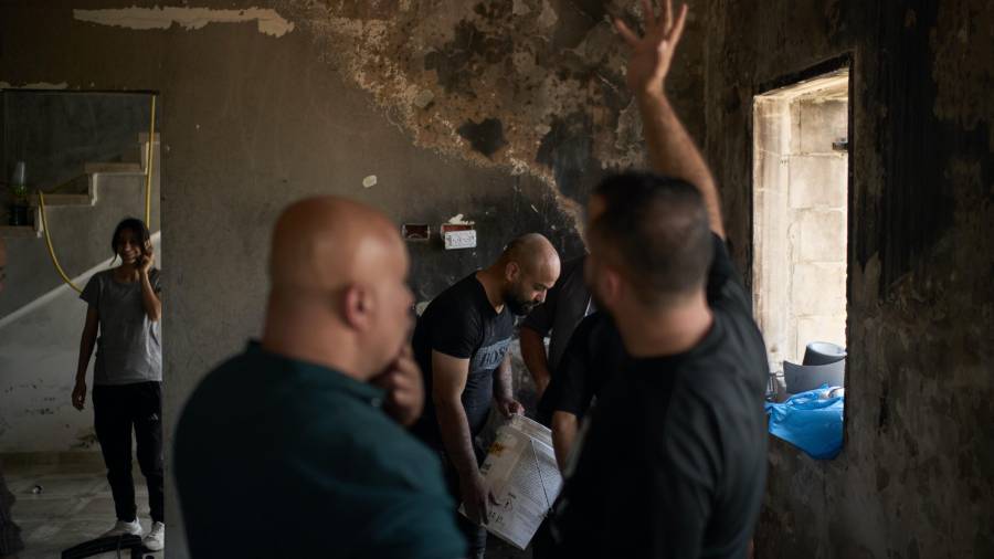 Varios palestinos se reúnen para reparar una vivienda dañada tras un ataque perpetrado el día anterior por colonos israelíes en el poblado de Sarra, cerca de la ciudad de Naplusa, Cisjordania.