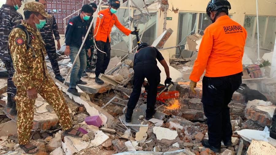 En esta fotografía difundida por la Agencia Nacional de Búsqueda y Rescate (BASARNAS) de Indonesia, equipos de rescate intentan retirar escombros de un edificio.