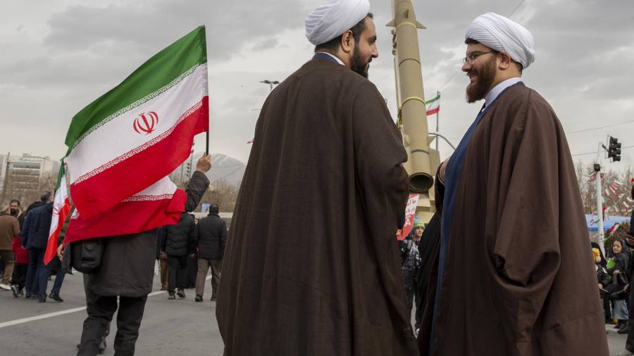Dos clérigos hablan entre sí cerca de un misil en exhibición para conmemorar el 47º aniversario de la Revolución Islámica en Teherán.