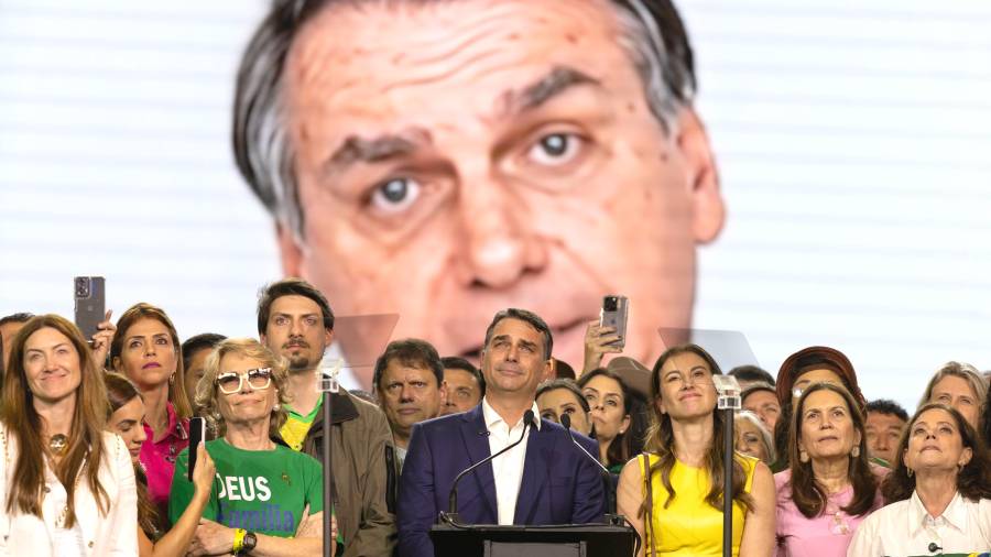 El senador Flávio Bolsonaro (c) reacciona durante la transmisión de un video de su padre, el expresidente Jair Bolsonaro enviando un mensaje de apoyo, en la convención nacional del Partido Liberal (PL).