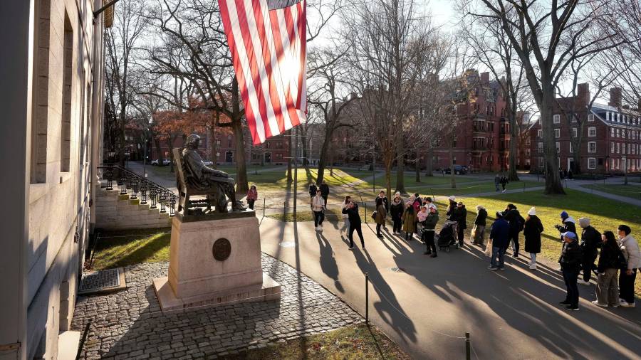 Unas personas toman fotos a la estatua de John Harvard, en la Universidad de Harvard.