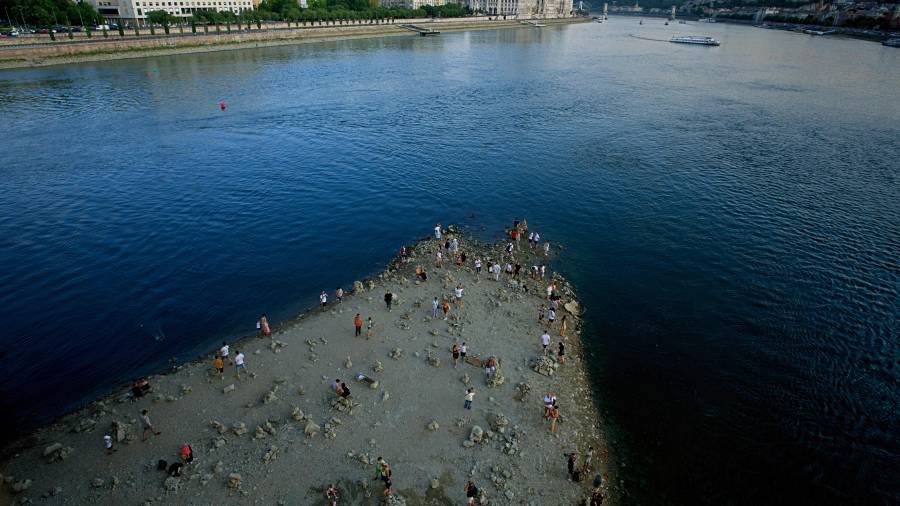 Personas caminan por un banco de arena bajo el puente Margarita del río Danubio, en el centro de Budapest, Hungría, mientras el río, que atraviesa diez países europeos, ha descendido a niveles de caudal nunca vistos.