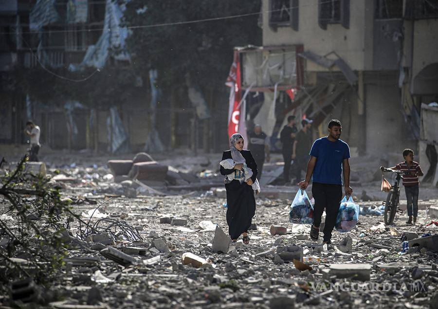 $!Una familia palestina se abre paso entre los escombros de los edificios alcanzados en un bombardeo israelí sobre el barrio de Tel al-Hawa, en Ciudad de Gaza.