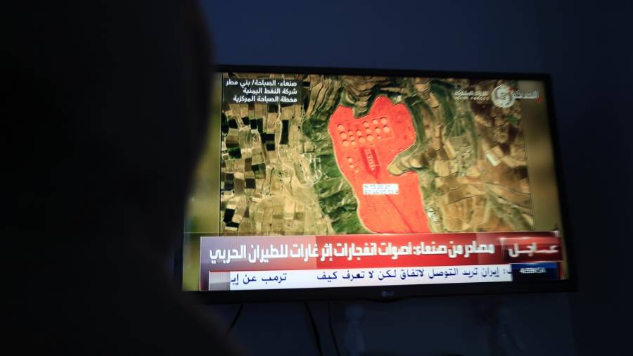 Una persona observa una TV que muestra la ubicación de una instalación de almacenamiento de petróleo en Saná, Yemen.