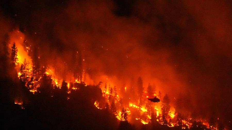 Un helicóptero que realiza operaciones nocturnas se prepara para arrojar agua sobre el incendio forestal de Quilpituk Creek, en la orilla occidental del lago Okanagan cerca de Fintry, Columbia Británica, Canadá.