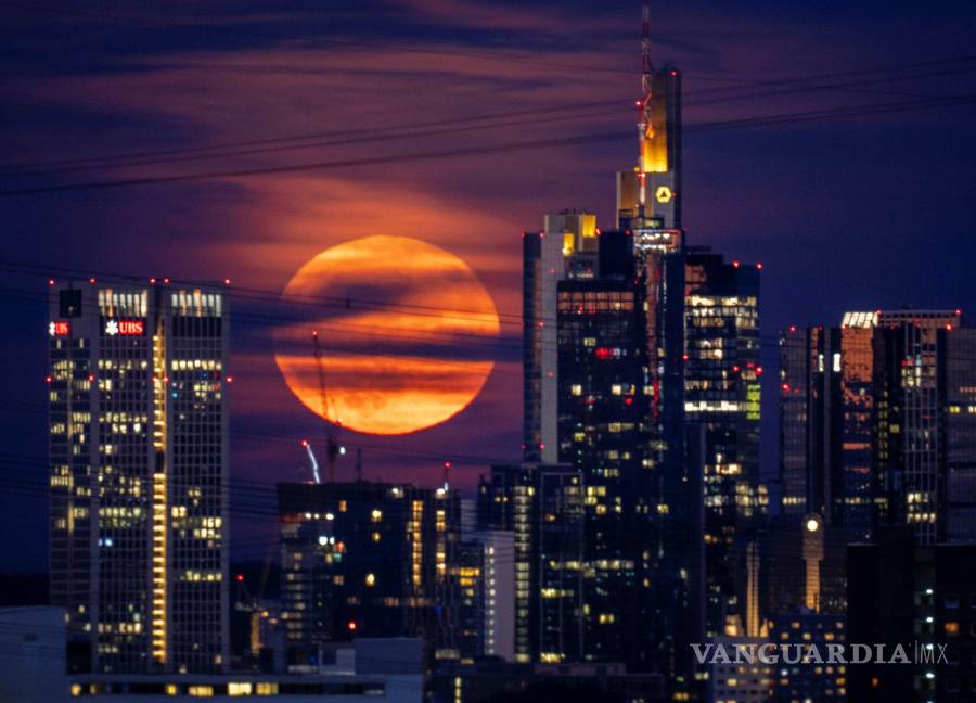 $!La luna llena se eleva detrás de los edificios en el distrito bancario de Frankfurt, Alemania. Durante un fenómeno conocido como la “ Strawberry Moon”.
