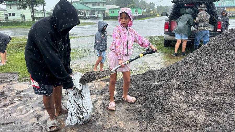 Kenzielynn Kekoa (centro), de Hilo, Hawai, ayuda a su familia a llenar sacos de arena ante la cercanía del huracán Nolo, el 25 de septiembre de 2026, en Hilo, Hawai.