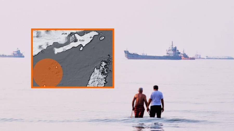 Dos hombres caminan en las aguas del estrecho de Ormuz con barcos fondeados más lejos, cerca de Bandar Abbas, Irán, el domingo 12 de julio de 2026, informó la AP.
