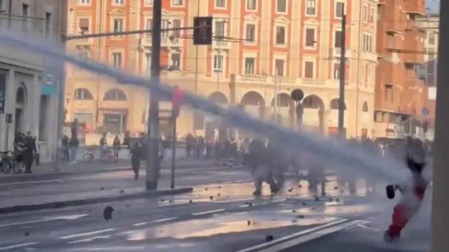 La mujer caminaba con paso firme cerca del frente de la multitud, vestida con ropa llamativa, antes de que un chorro directo de agua a alta presión la arrojara al suelo.