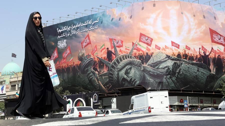 Una mujer iraní con velo pasa junto a una valla publicitaria antiamericana en la plaza Enghelab, en el centro de Teherán, Irán, el 3 de agosto de 2026.