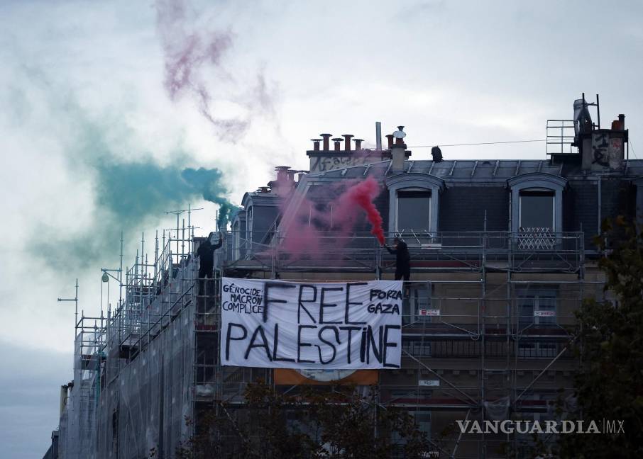 $!Dos manifestantes queman velas de humo en lo alto de un edificio junto a una pancarta de “Palestina libre”, para apoyar al pueblo palestino, en París, Francia.