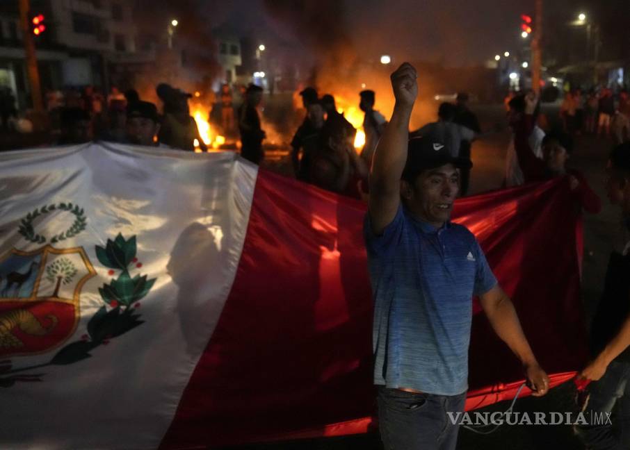 $!Un manifestante lanza proclamas contra el gobierno mientras otros llevan una bandera nacional durante el bloqueo de la autopista Panamericana Norte en Chao, Perú, el viernes 17 de febrero de 2023.