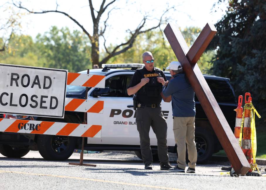 $!Dan Beazley, con su cruz de 3 metros, es detenido por un agente del sheriff cerca de la Iglesia de Jesucristo de los Santos de los Últimos Días en Grand Blanc, Michigan.