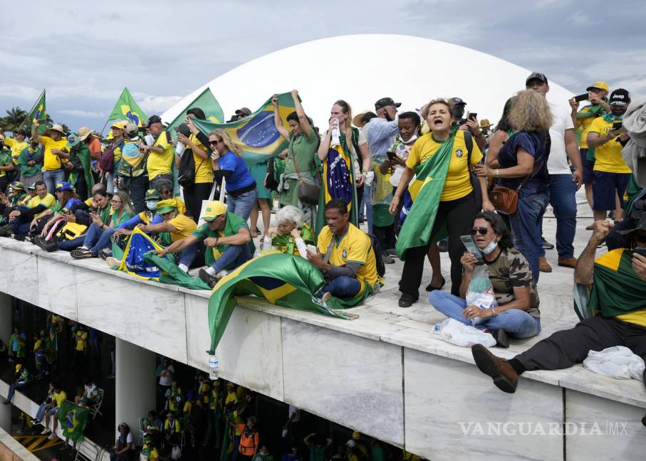$!Los manifestantes, partidarios del expresidente de Brasil, Jair Bolsonaro, se paran en el techo del edificio del Congreso Nacional después de que lo asaltaron.