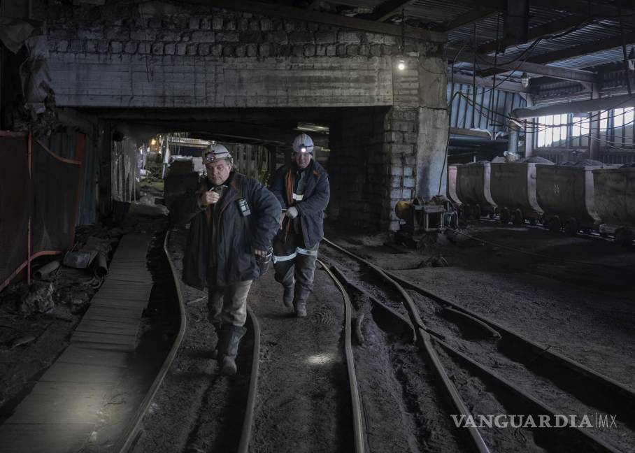 $!Trabajadores pasan junto a carros mineros llenos de carbón en una mina de Barentsburg, en Svalbard al oeste del norte de Groenlandia.