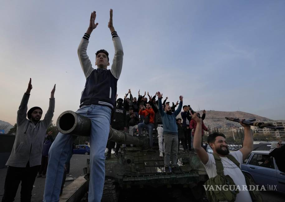 $!Ciudadanos sirios sobre un tanque de las fuerza gubernamentales abandonado sobre una calle celebraban la toma de la ciudad a manos de los insurgentes.