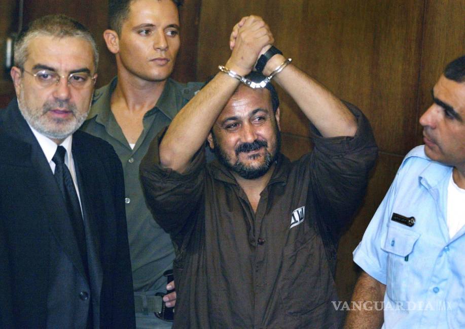 $!Marwan Barghouti, en el centro, levanta sus manos esposadas en el aire el primer día de su juicio en Tel Aviv, Israel, el 14 de agosto de 2002.