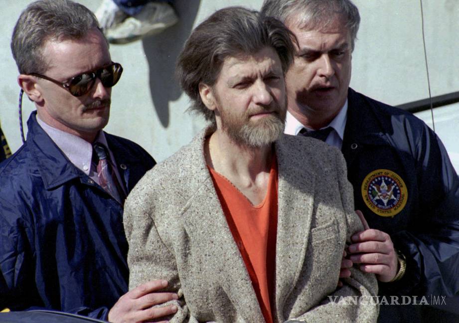 $!Theodore Ted Kaczynski es escoltado a su auto afuera de una corte federal en Helena, Montana, el 4 de abril de 1996.