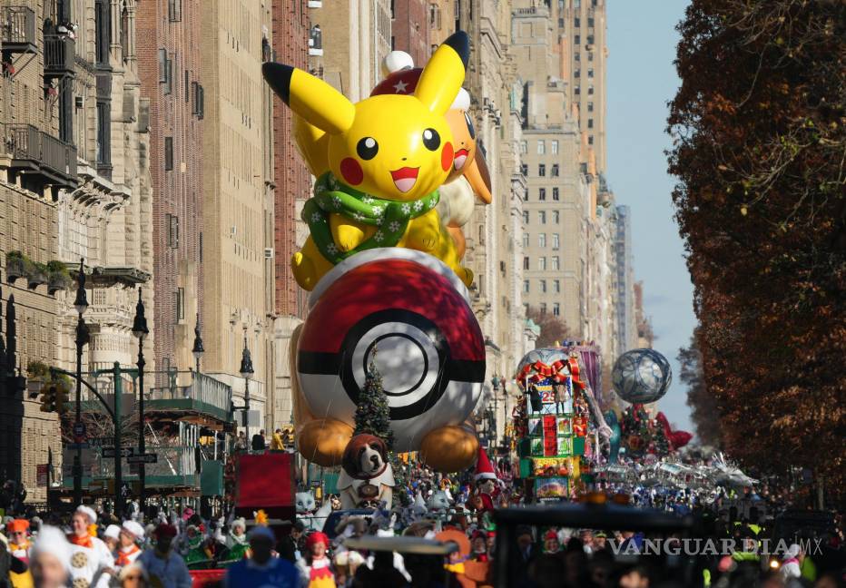 $!Los manejadores guían el globo de Pikachu y Eevee a lo largo de Central Park West durante el desfile del Día de Acción de Gracias de Macy’s en Nueva York.