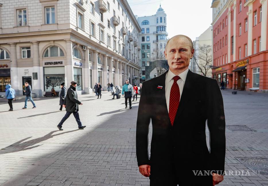 $!La gente pasa junto a una figura de cartón del presidente ruso y candidato presidencial Vladimir Putin en la calle de Moscú, Rusia.