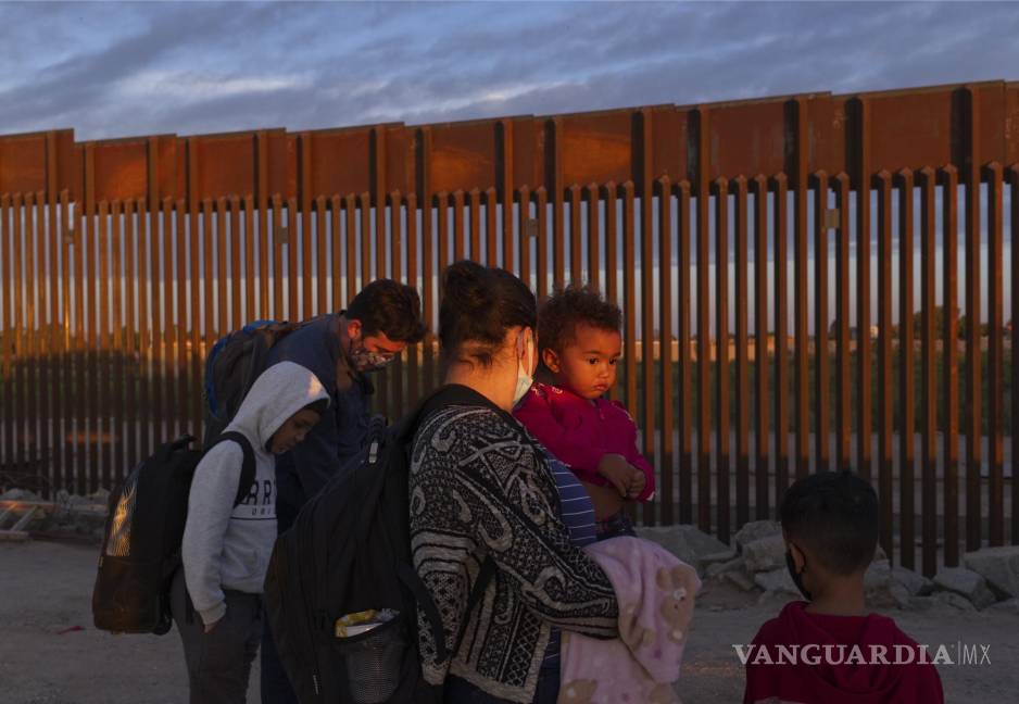 $!Migrantes esperan a ser procesados por agentes fronterizos de EU, tras pasar por una brecha en el muro, en Yuma, Arizona.