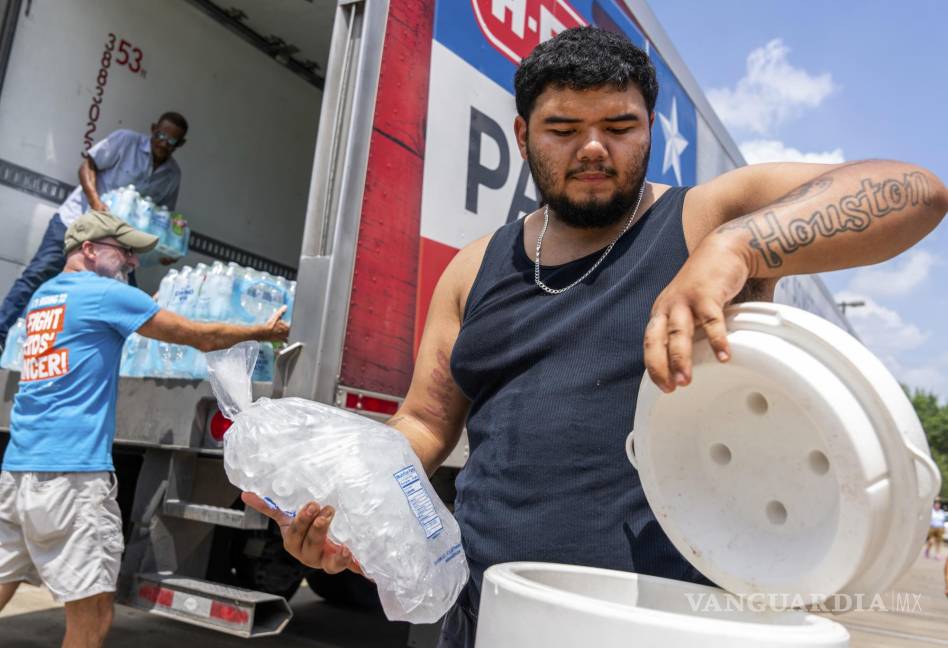 $!Daniel Valdez coloca una bolsa de hielo en una hielera mientras los voluntarios de Memorial Assistance Ministries distribuyen agua y hielo en Houston.