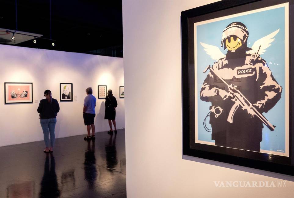 $!Personas cerca de la obra de arte ‘Flying Copper’ (R) mientras visitan la exposición ‘The Art of Banksy: Without Limits’. EFE/EPA/Cristobal Herrera-Ulashkevich