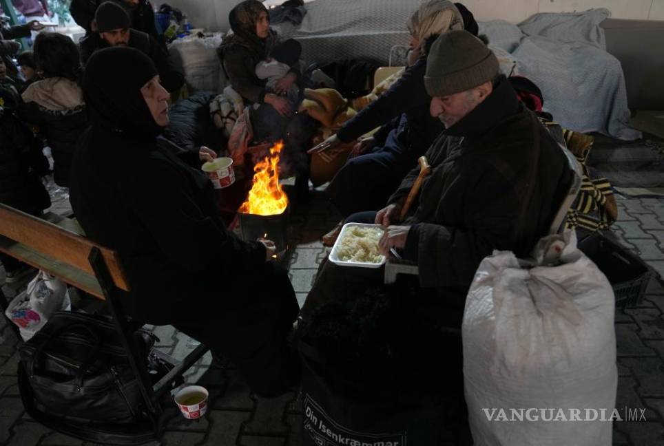 $!Varios sirios se calientan en torno al fuego en un refugio en Antakya, en el sureste de Turquía.