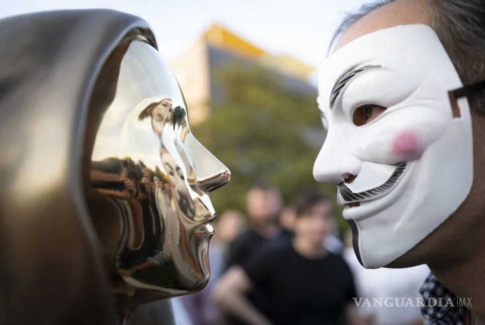 $!Un hombre que llevaba una máscara de Guy Fawkes mira una estatua recién revelada del misterioso desarrollador de la moneda digital Bitcoin en Budapest, Hungría. AP/Bela Szandelszky