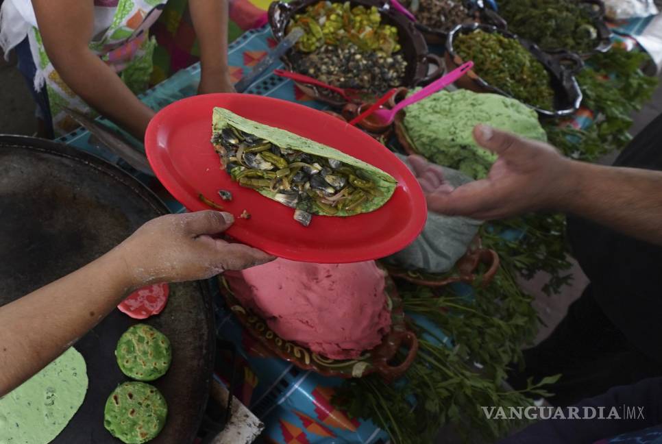 $!Un vendedor sirve nopales y huitlacoche en una tortilla de color verde en la Feria de Comida Prehispánica en la alcaldía Iztapalapa de la Ciudad de México.