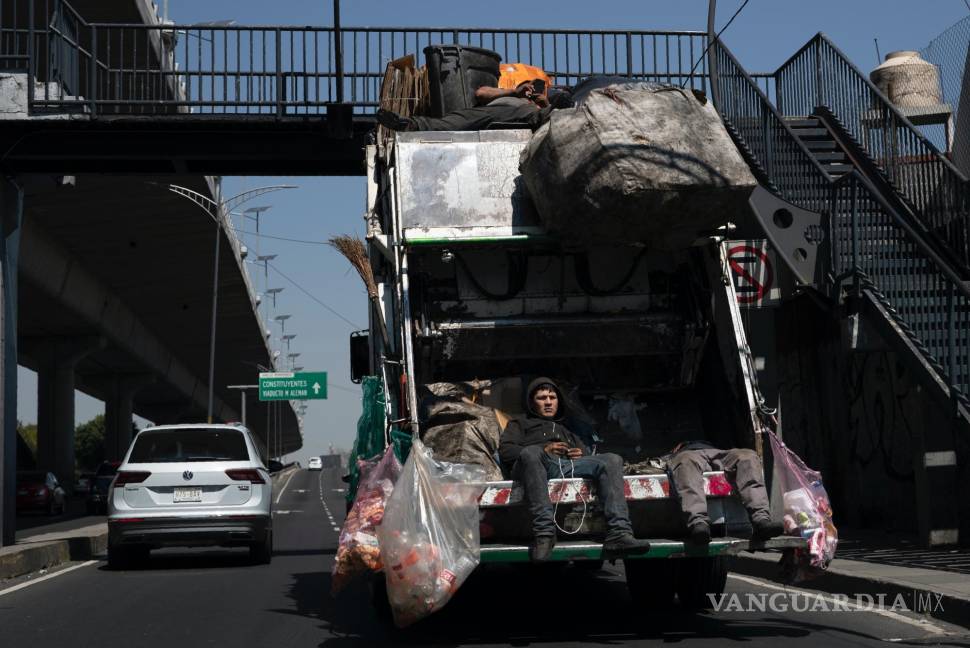 $!Recolectores de basura viajan en su camión de basura en la Ciudad de México, el martes 6 de octubre de 2020.
