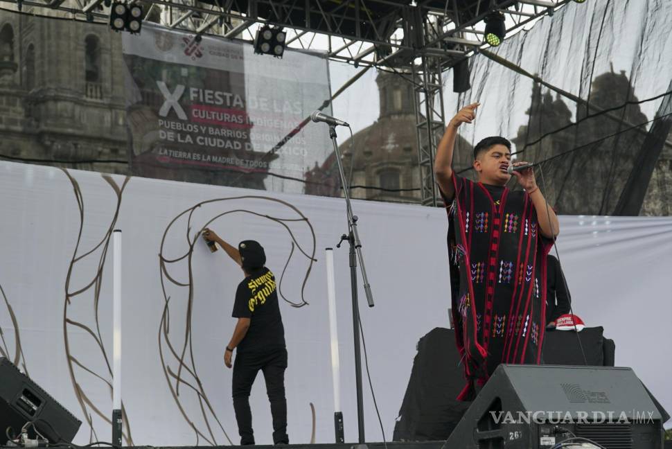 $!El rapero mexicano-triqui Carlos CGH canta mientras el artista Alberto Sebastián Bautista Figueroa hace un grafiti en el Zócalo de la Ciudad de México.