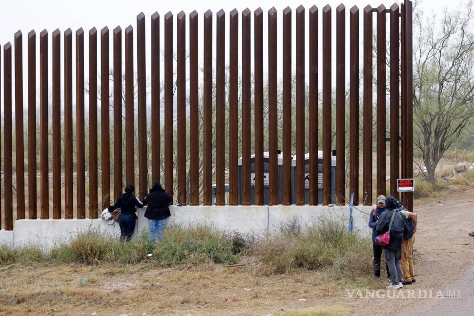 $!Migrantes parados frente al muro fronterizo esperan ser recogidos por agentes de la Patrulla Fronteriza en Eagle Pass, Texas, el 14 de enero de 2024.