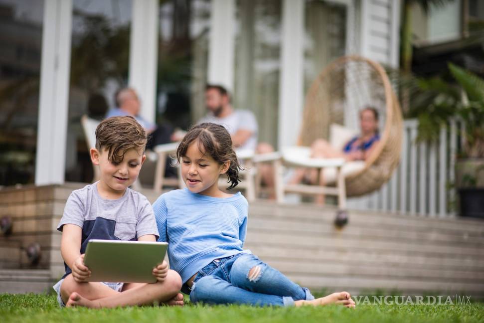 $!Niña y niño observando contenido digital en una 'tablet'.