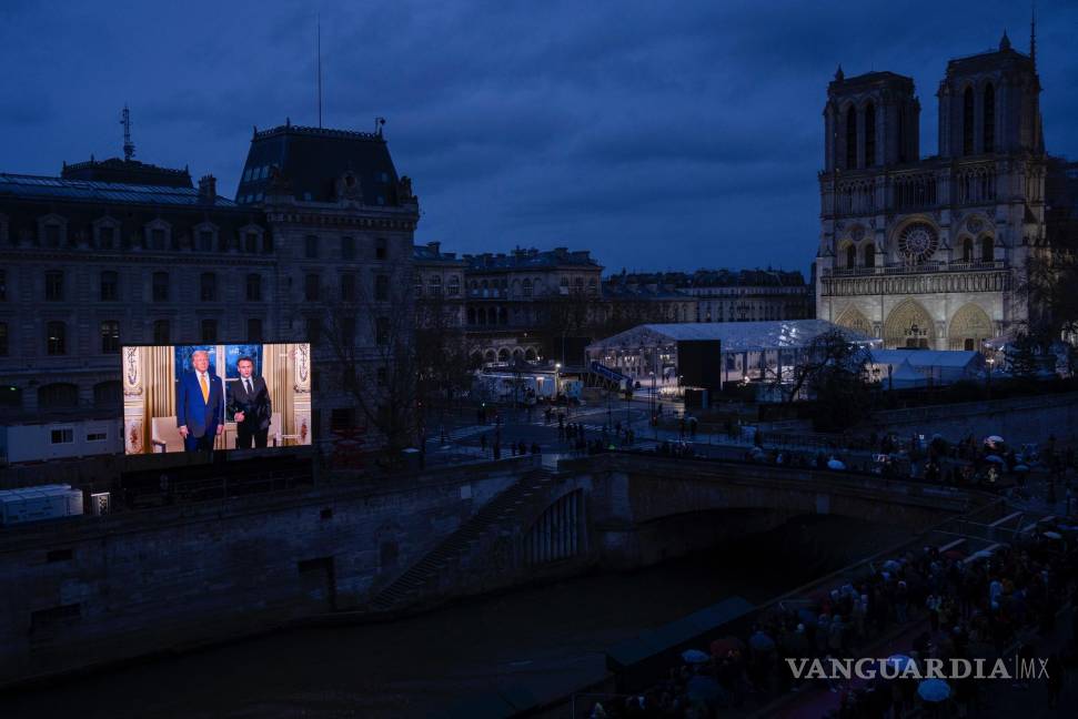 $!La reunión entre Donald Trump y Emmanuel Macron se muestra en una pantalla gigante para las multitudes reunidas cerca de la icónica catedral de Notre Dame.