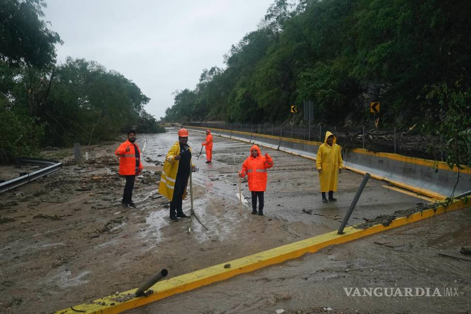 $!Trabajadores limpian una carretera bloqueada tras el paso del huracán Otis cerca de Acapulco, México.