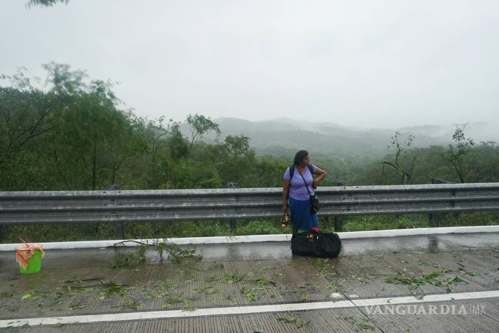 $!Una mujer que se bajó de un autobús parado en una carretera bloqueada por un deslizamiento de tierra provocado por el huracán Otis cerca de Acapulco, México.