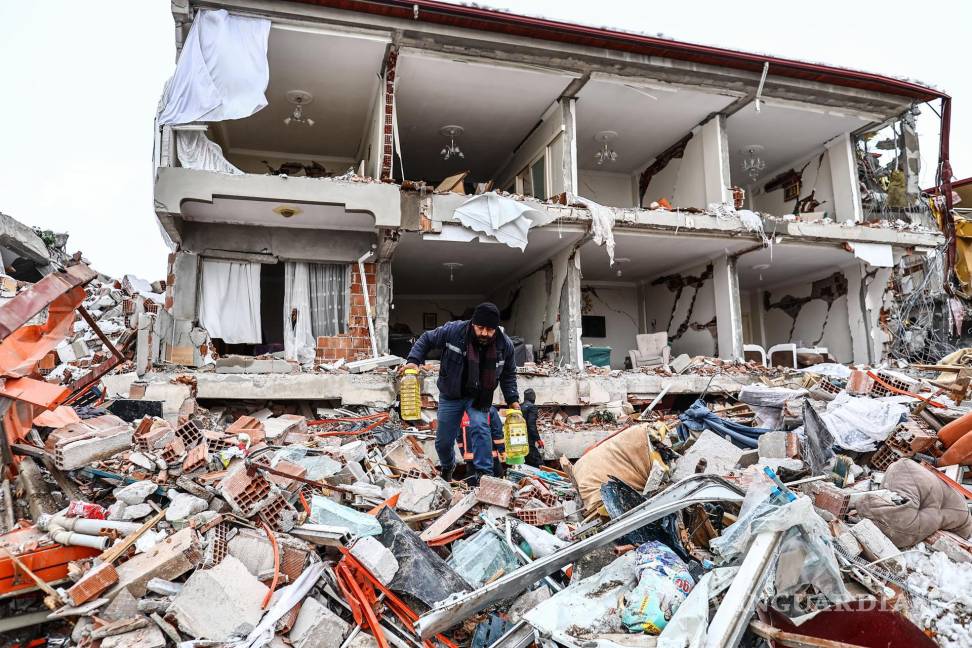 $!Las personas llevan alimentos rescatados de un edificio derrumbado después de un poderoso terremoto en el distrito de Elbistan de Kahramanmaras, Turquía.