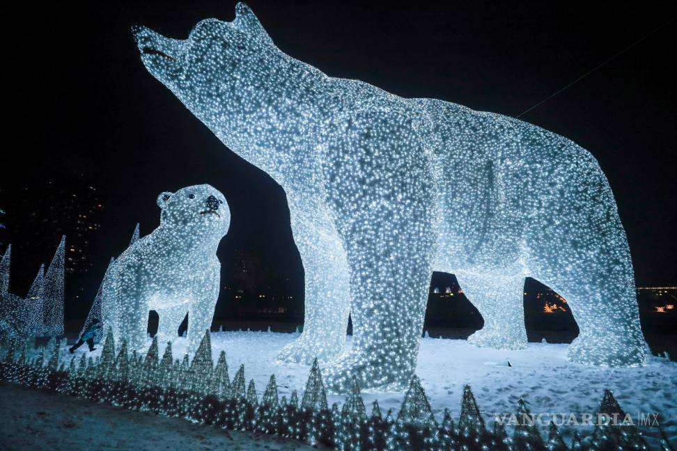 $!Un niño corre cerca de enormes esculturas de luz de osos polares que se instalaron como parte de una decoración navideña en Moscú, Rusia. EFE/EPA/Sergei Ilnitsky