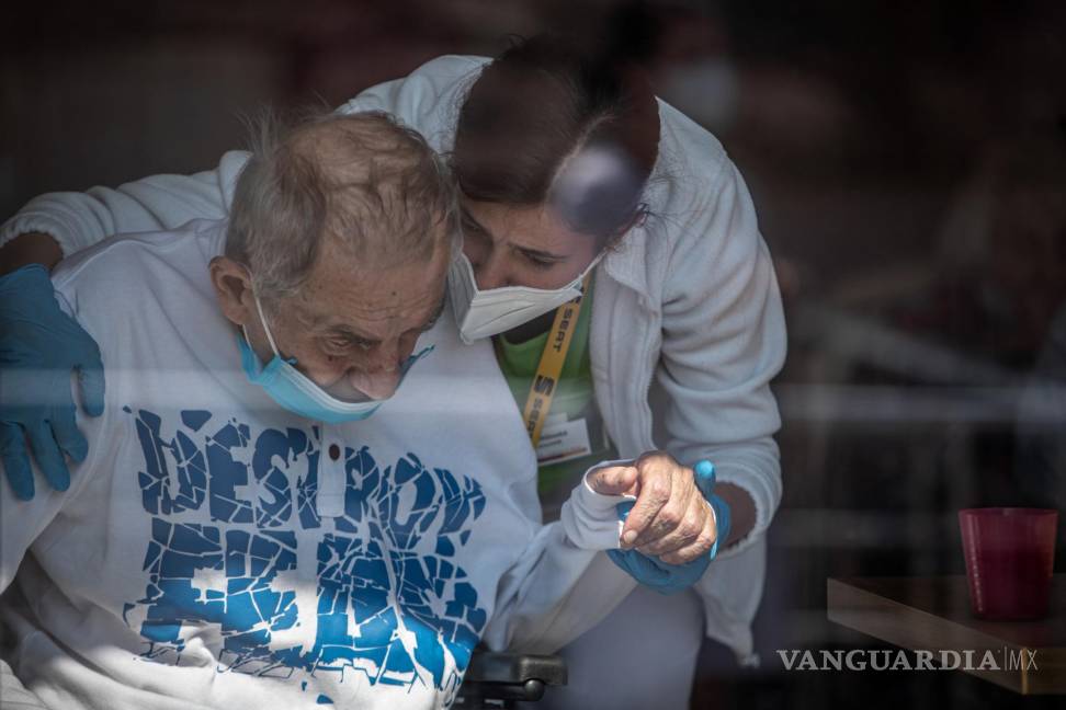 $!Un sanitario con mascarilla sostiene la mano de un residente de una casa de Alzheimer en Pitkovice, República Checa. EFE/EPA/Martin Divisek