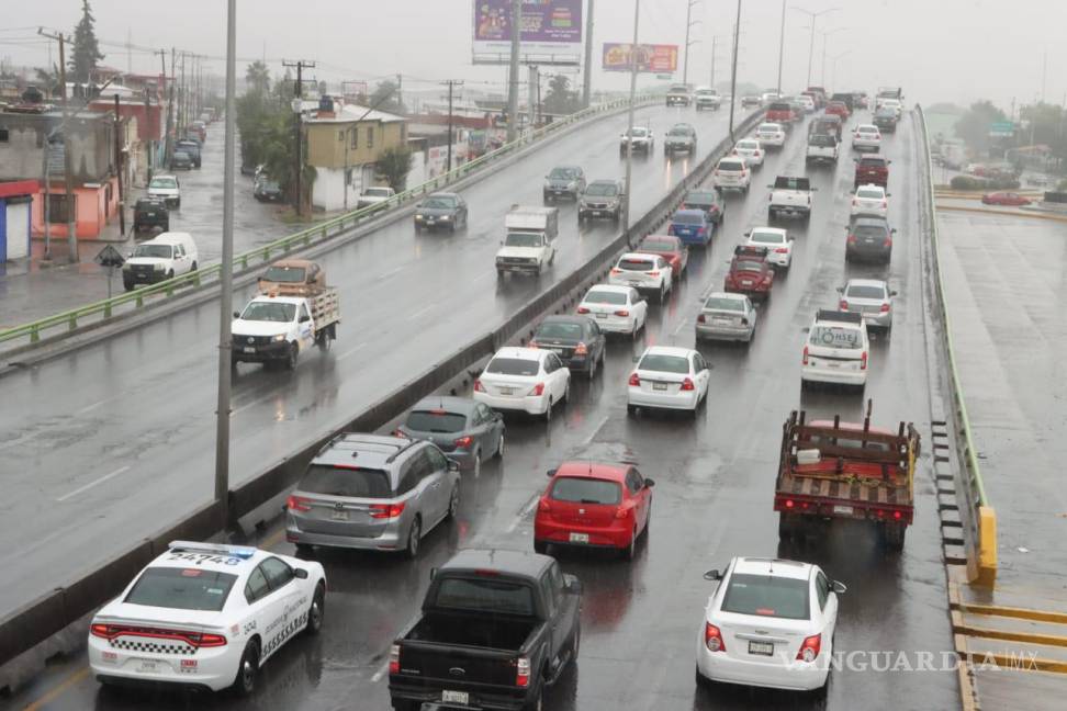 $!Vehículos circulando por una carretera mojada debido a las intensas lluvias, destacando la importancia de conducir con precaución.