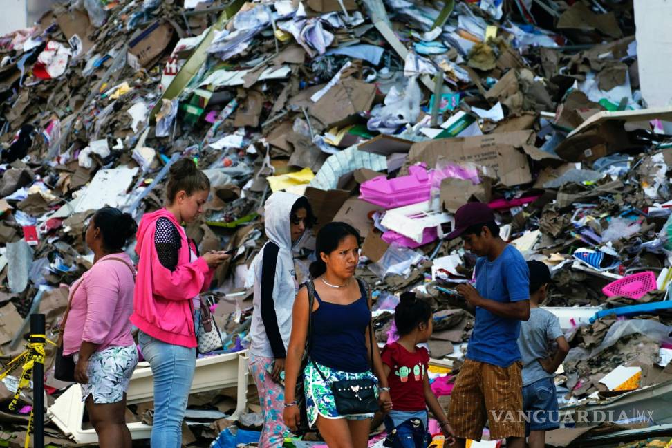 $!Residentes caminan al lado de una montaña de basura tras la devastación que dejó el paso del huracán Otis, en Acapulco, México, el domingo 12 de noviembre de 2023.