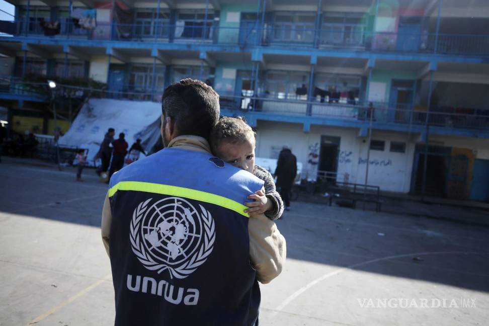 $!Un niño gazatí es ayudado por un miembro de la Agencia de Naciones Unidas para la población refugiada de Palestina.