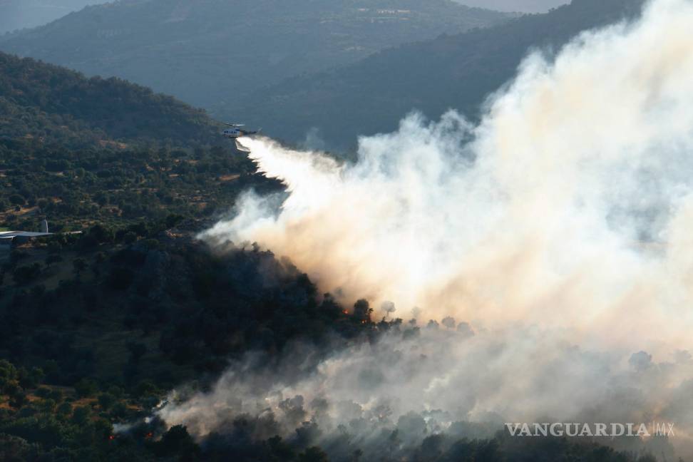 $!Un helicóptero de extinción de incendios arroja agua para extinguir el fuego en la aldea de Agia Galini en el municipio de Agios Vassilios, Rethimno, Grecia.
