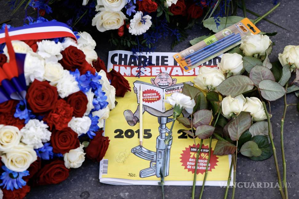 $!Una edición especial del periódico satírico francés Charlie Hebdo entre coronas de flores y lápices dejados frente a las antiguas oficinas de Charlie Hebdo.