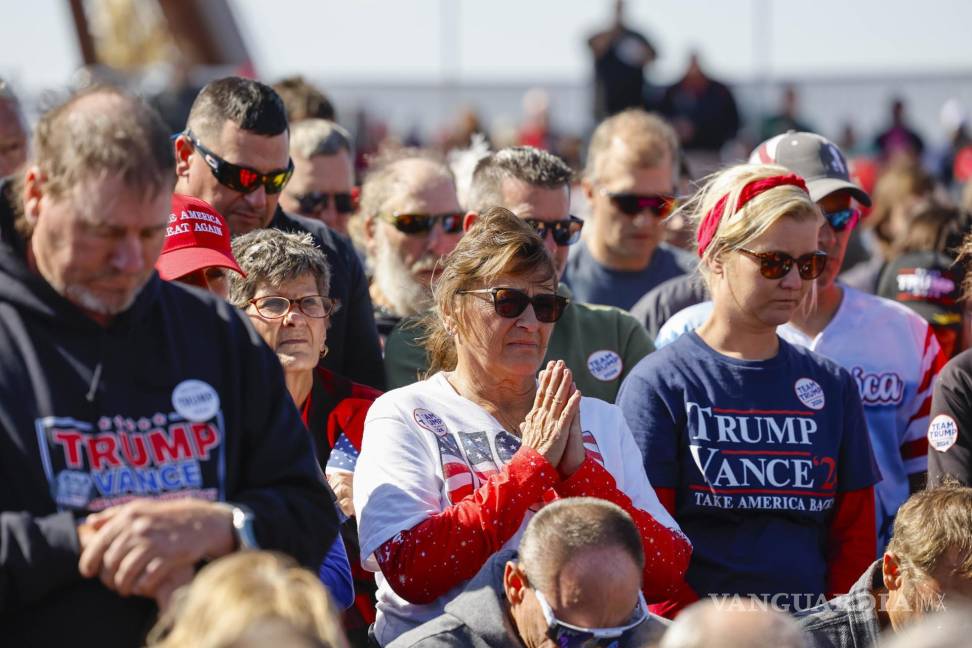 $!Partidarios rezan antes de que Donald Trump hable durante un mitin de campaña en el aeropuerto del condado de Dodge en Juneau, Wisconsin.