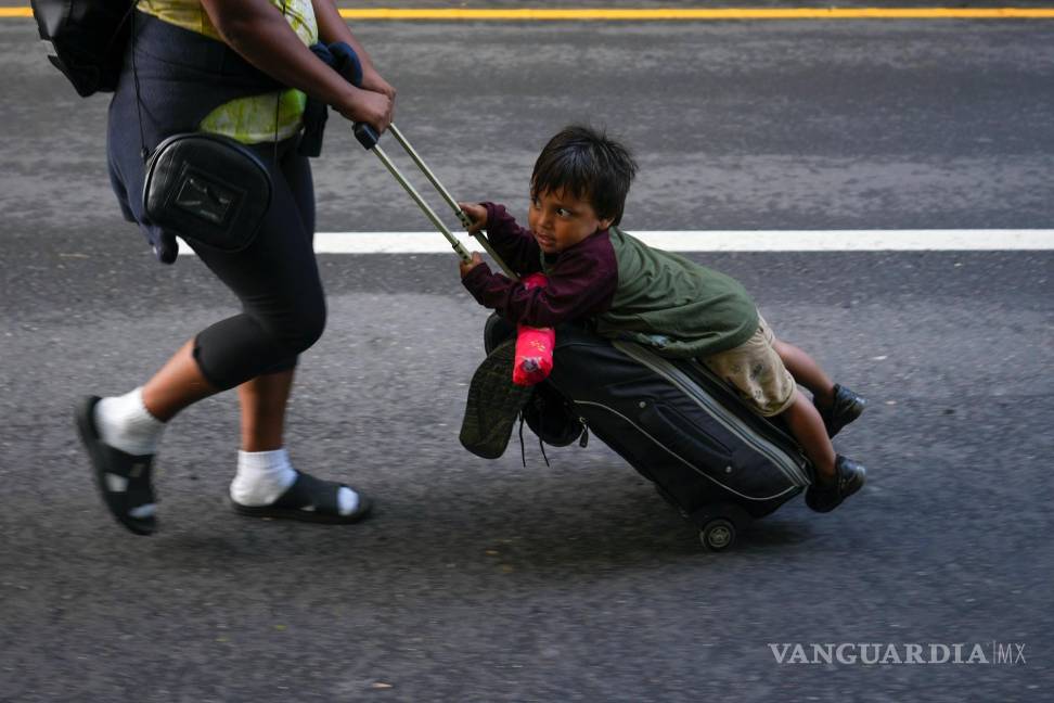 $!Nayely Núñez, de Honduras, utiliza su maleta como carro para mover a un niño mientras camina junto a una caravana de migrantes por una carretera en Huixtla.